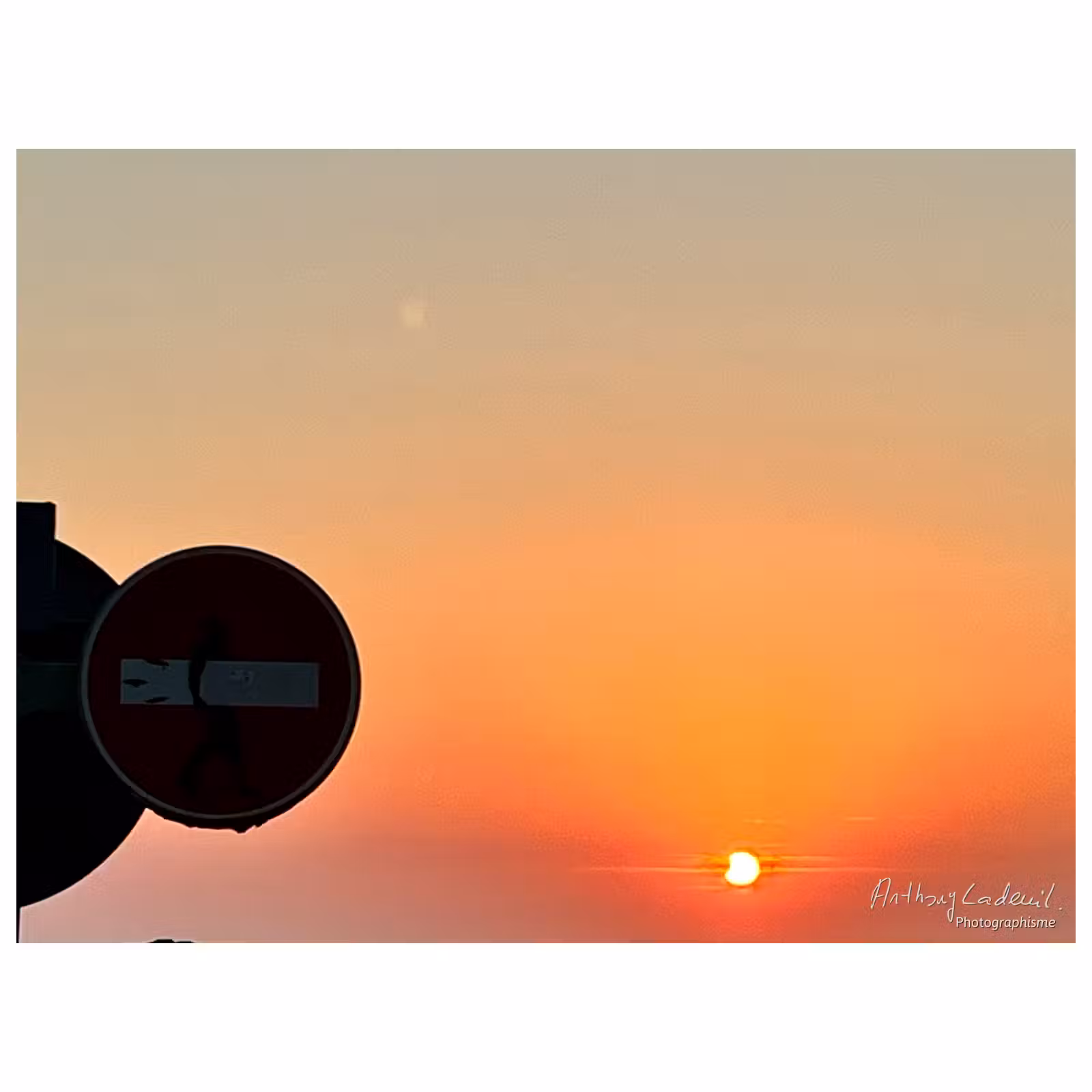 Coucher de soleil après l'éclipse du 12 aoüt 2026, avec un panneau de sens interdit au premier plan.