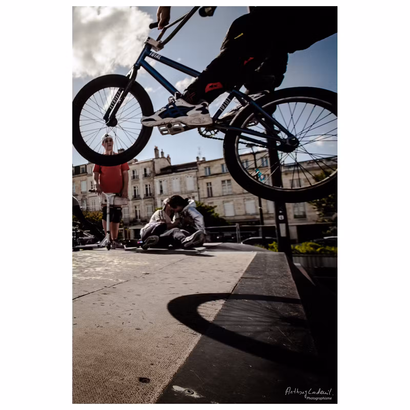 adolescent effectuant un saut à vélo BMX sur un tremplin avec des jeunes en arrière plan