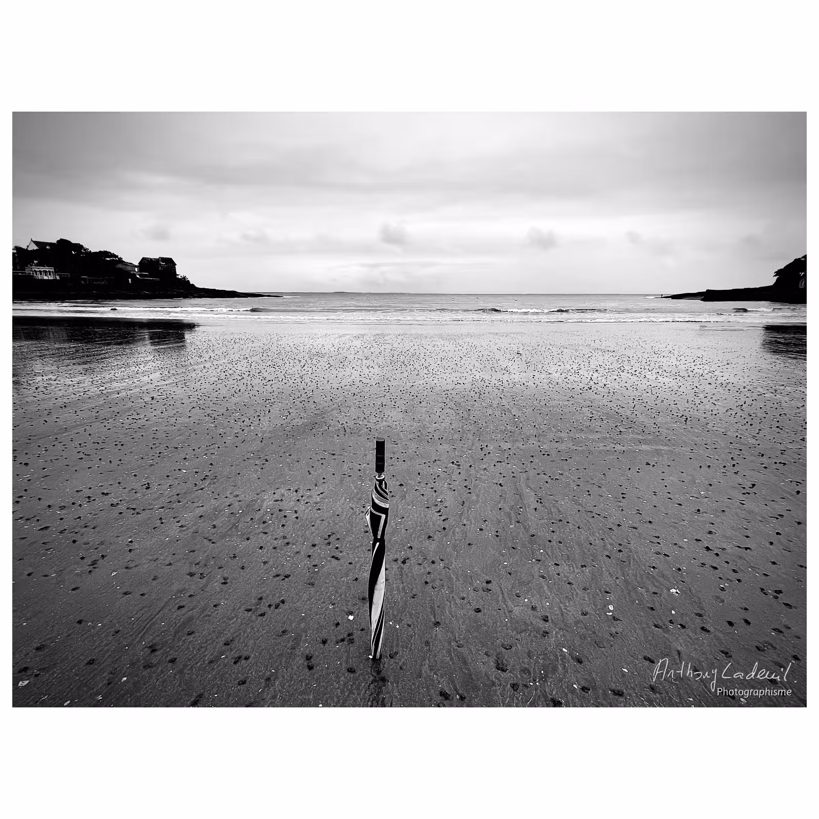 Plage de Saint Palais en noir et blanc, à marée basse, avec un parapluie planté dans le sable