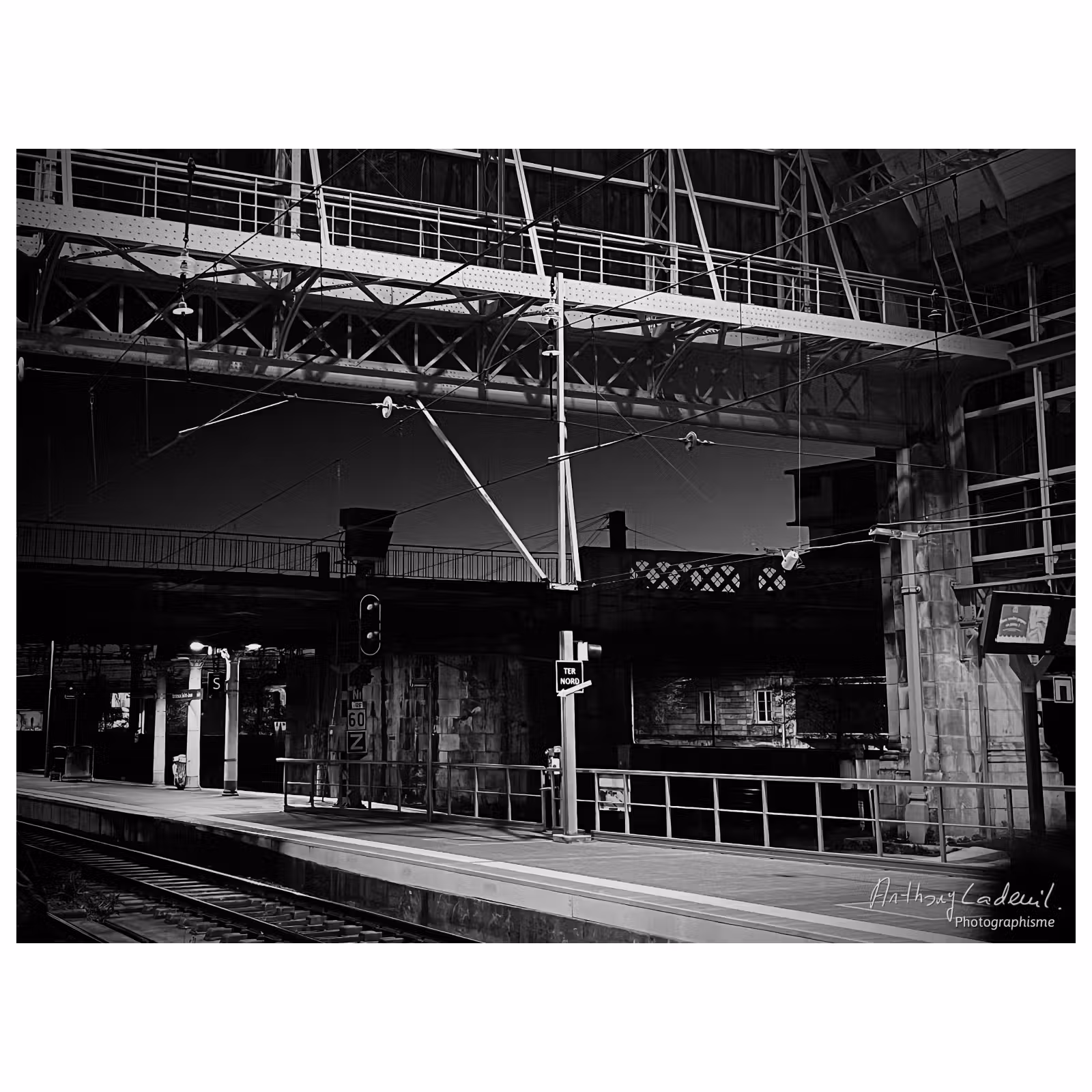 photographie en noir et blanc d'un quai de gare et une verrière métallique