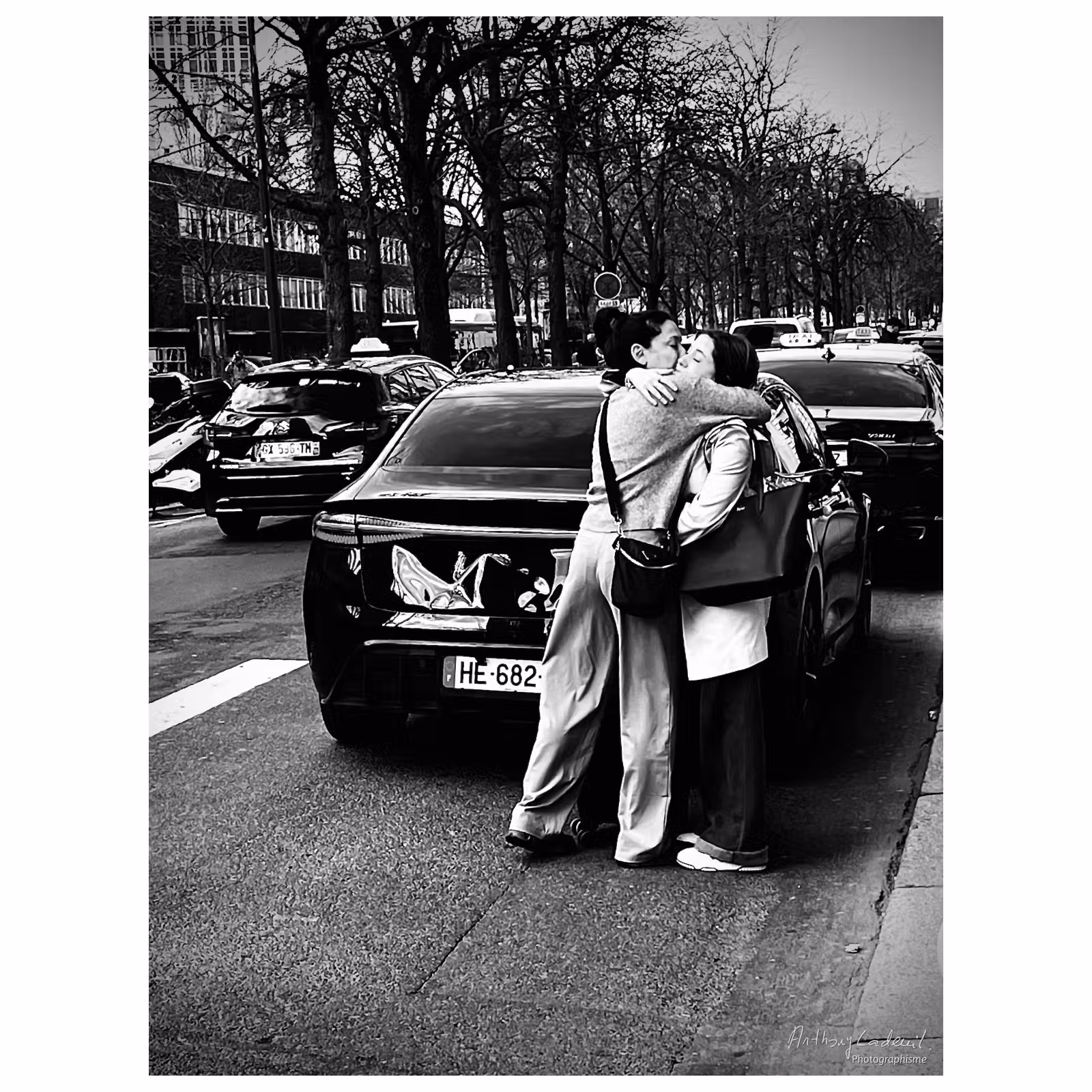 photographie en noir et blanc de deux femmes s'enlaçant tendrement dans la rue