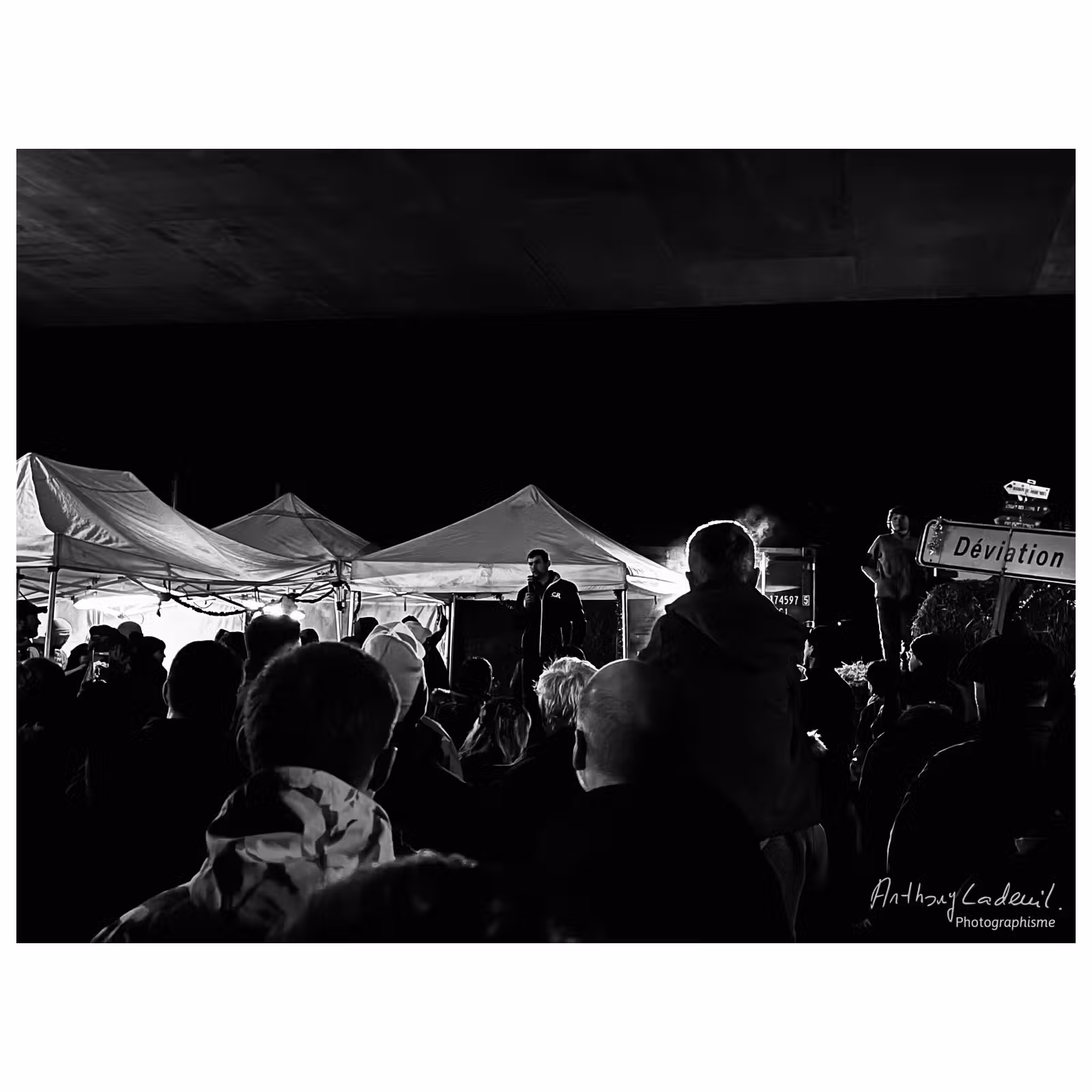 photo en noir et blanc d'agriculteurs manifestant sous un pont d'autoroute