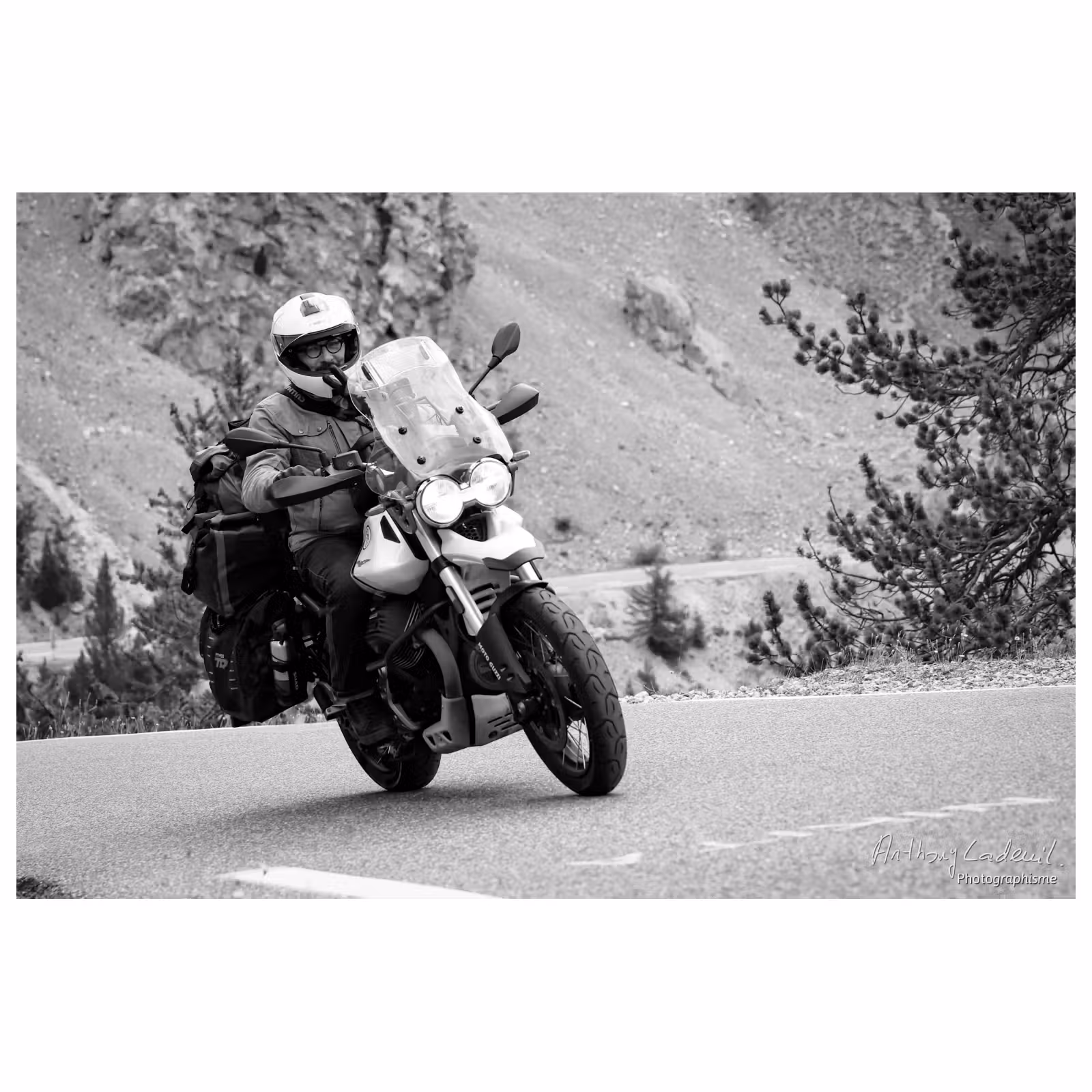 photo noir et blanc d'un motard sur une Moto Guzzi V85 TT chargée de bagages