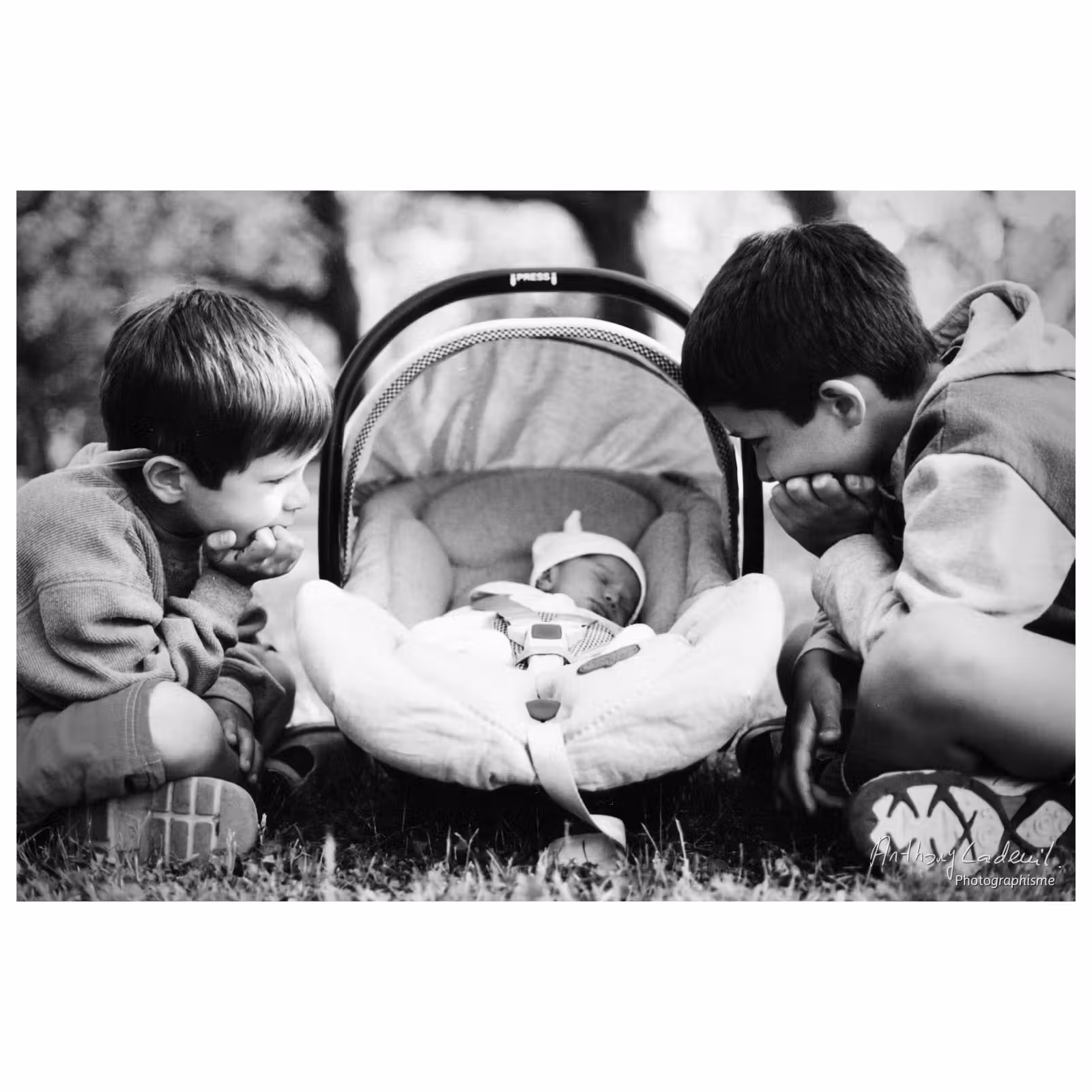 Deux jeunes enfants regardent un bébé dans couffin
