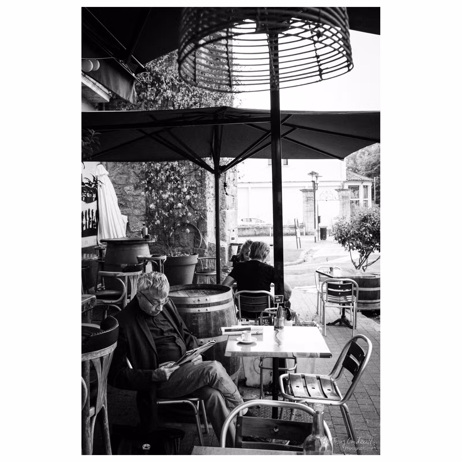 photographie d'un homme assis sur une terrasse de café lisant un journal