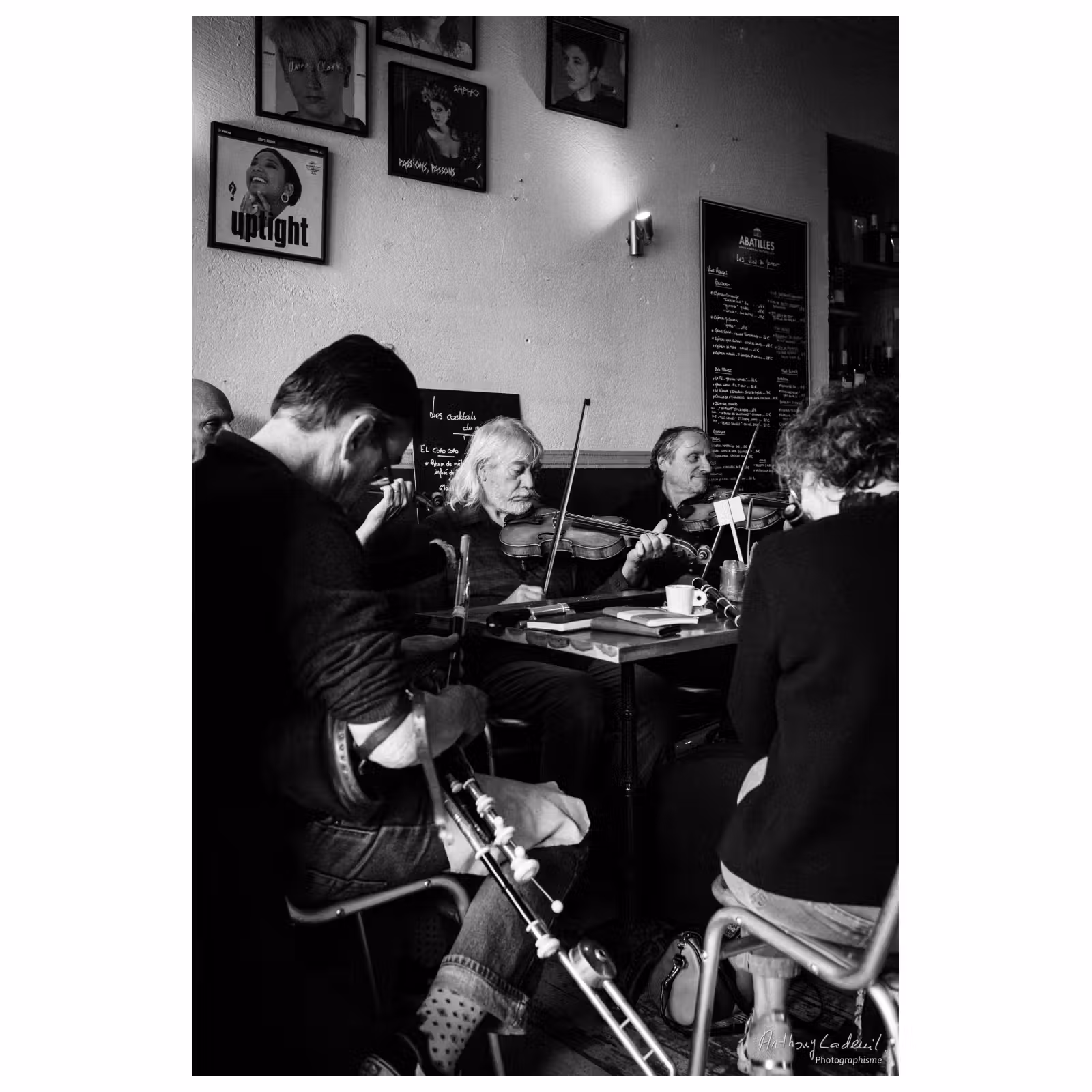 photographie d'un groupe de musiciens jouant assis autour d'une table dans un café