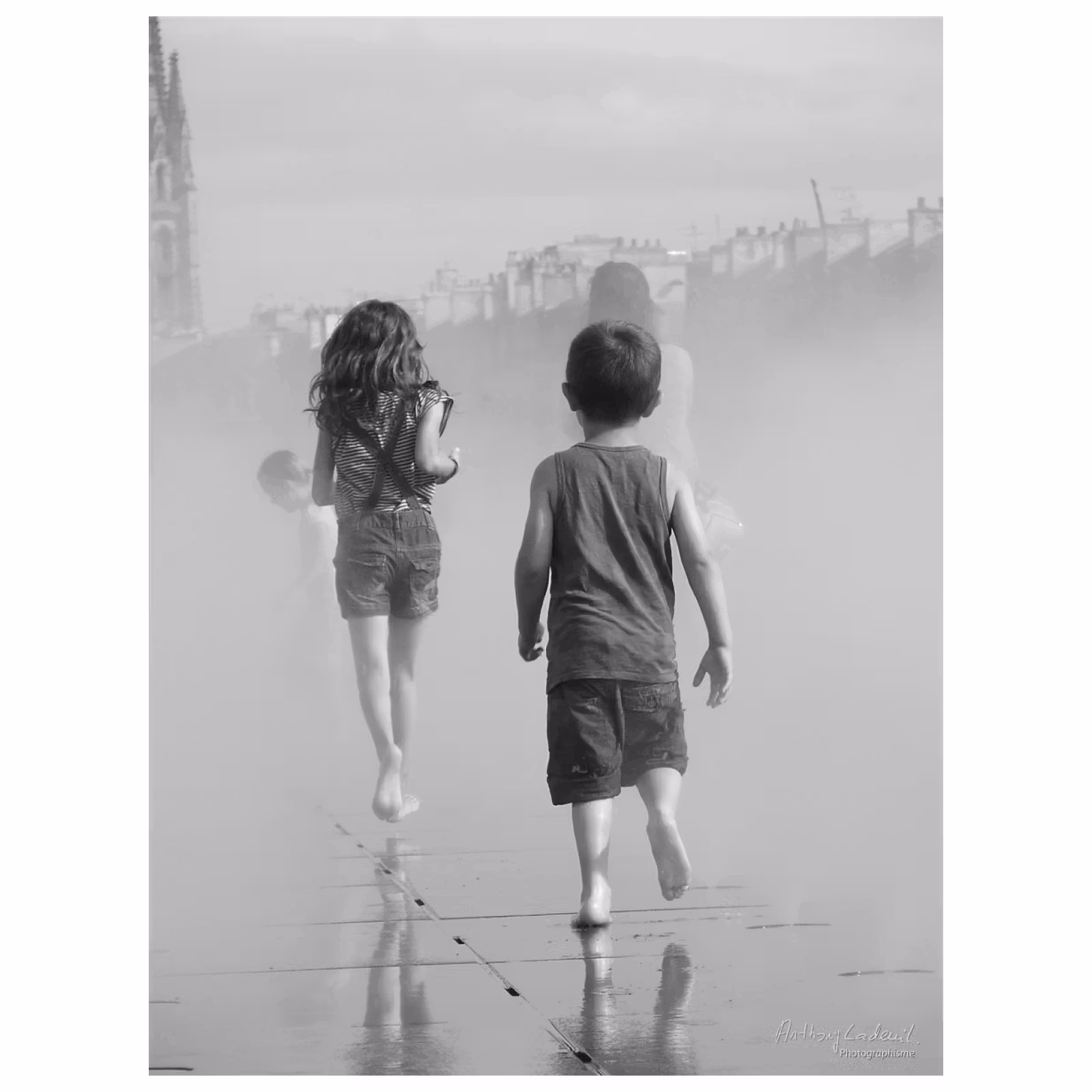 deux enfants de dos courent sur un miroir d'eau