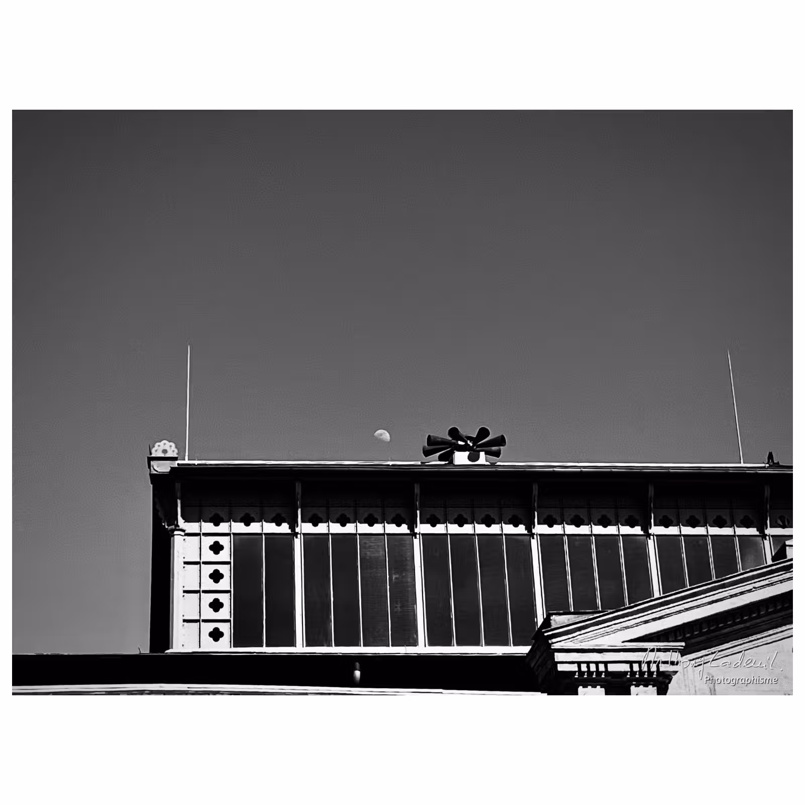 photographie du toit d'une halle avec la Lune en plein jour
