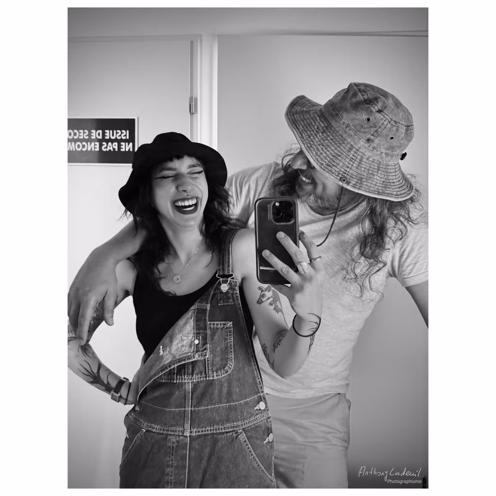 une jeune femme rit en faisant un selfie avec son père. Les deux portent des chapeaux.