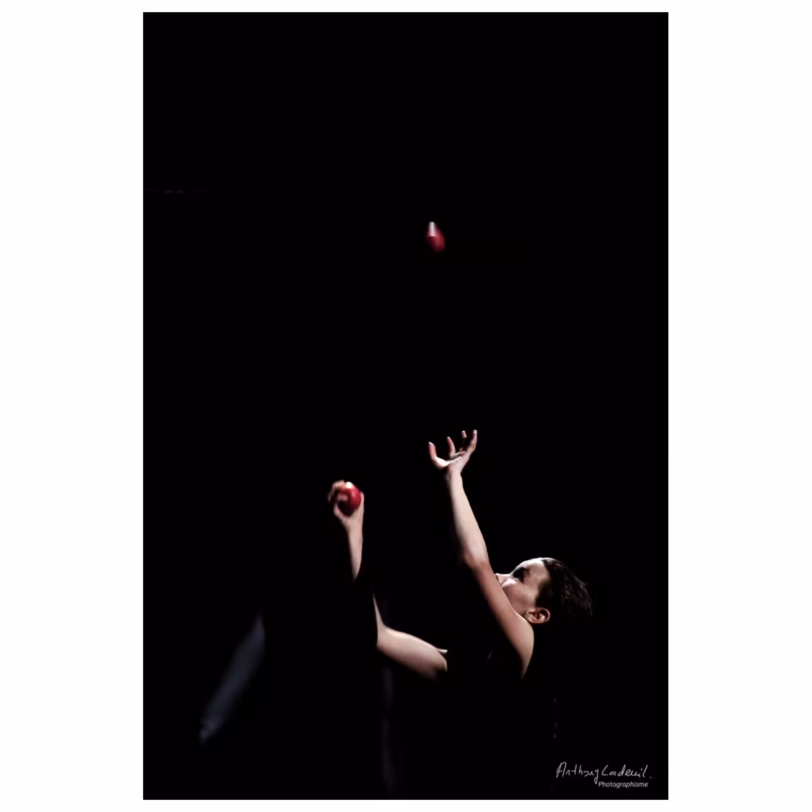 photographie d'un enfant dans le noir lançant une balle rouge