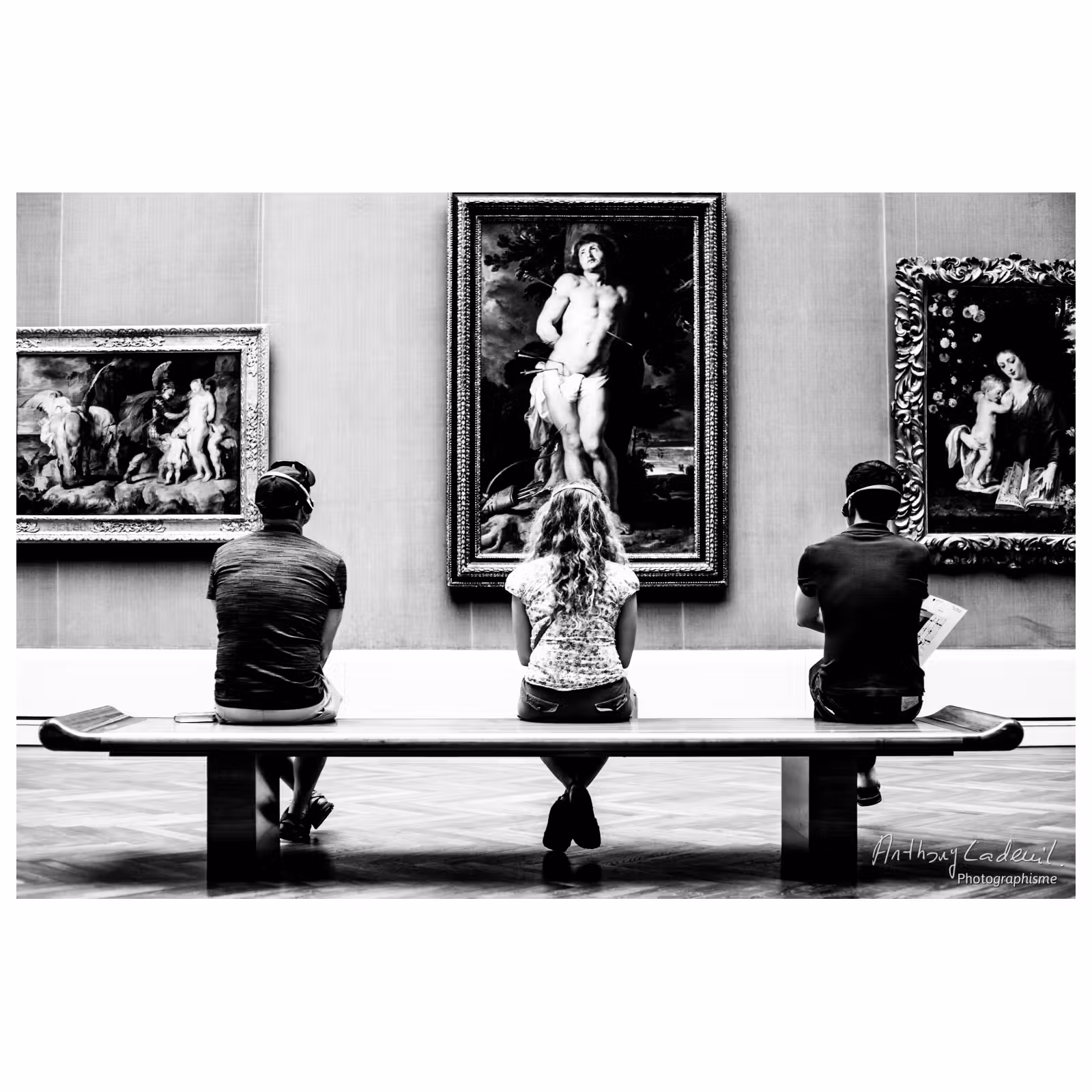 trois personnes de dos assises dans un musée regardent chacune un tableau