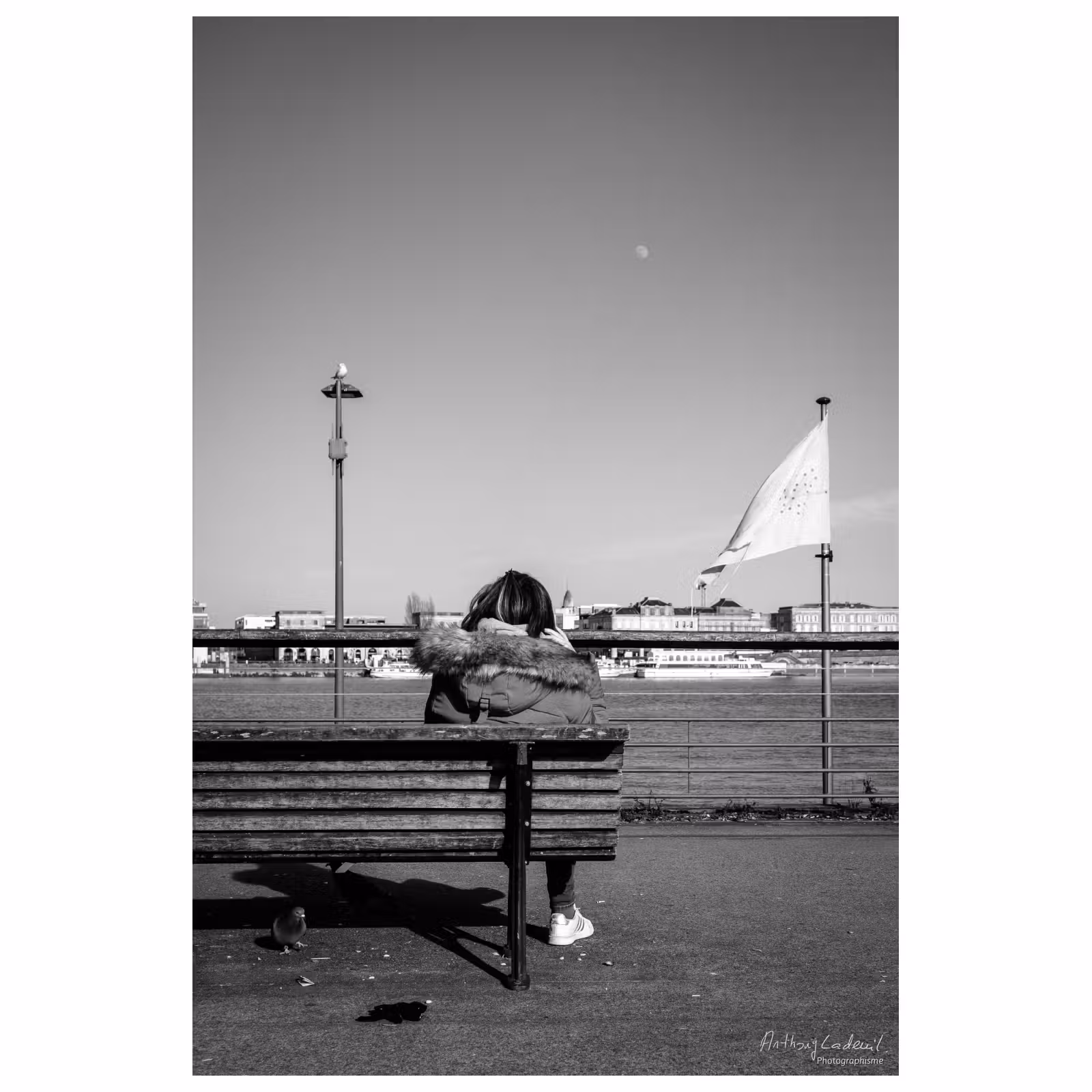 photo noir et blanc d'une personne assise sur un banc public
