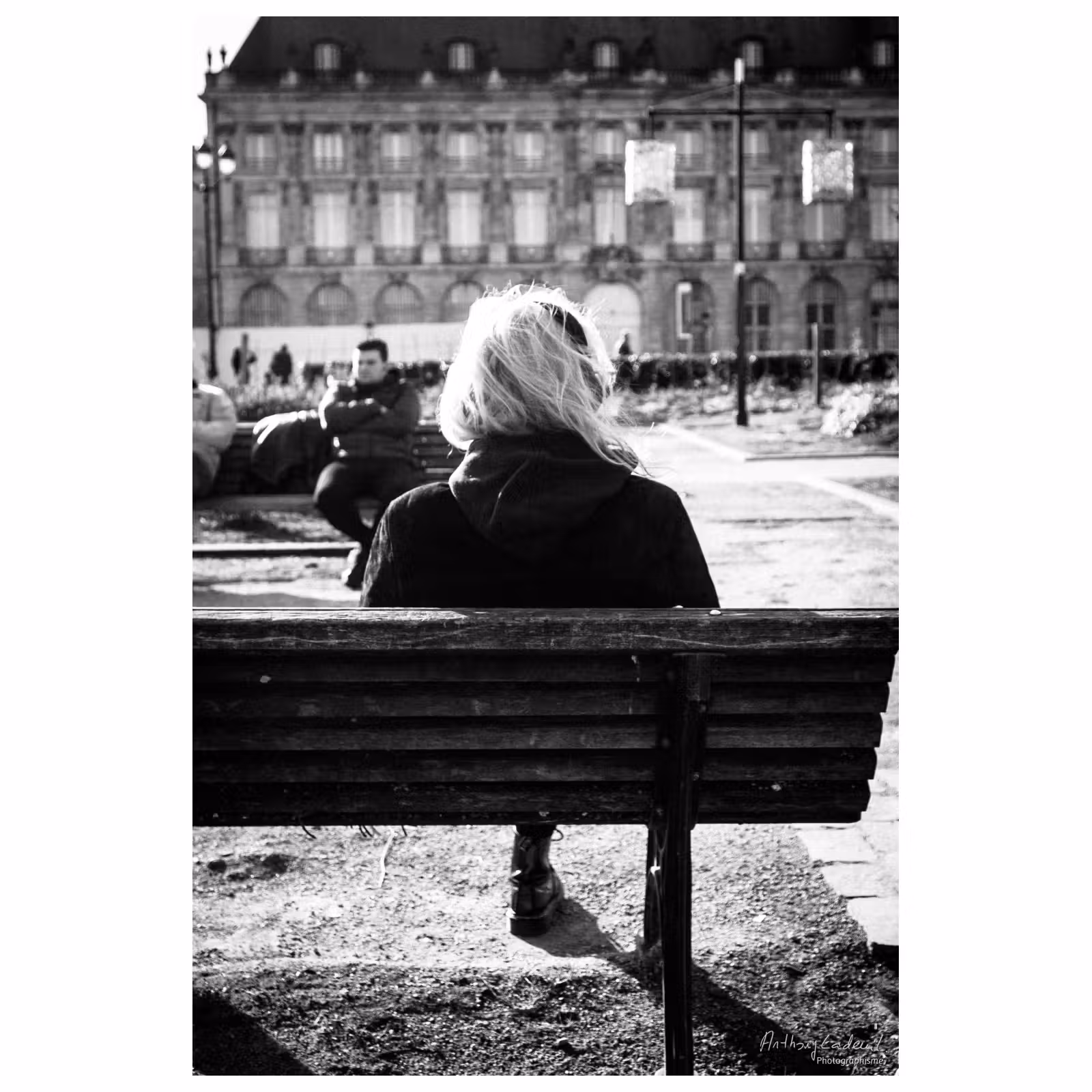 photo noir et blanc d'une personne assise sur un banc public