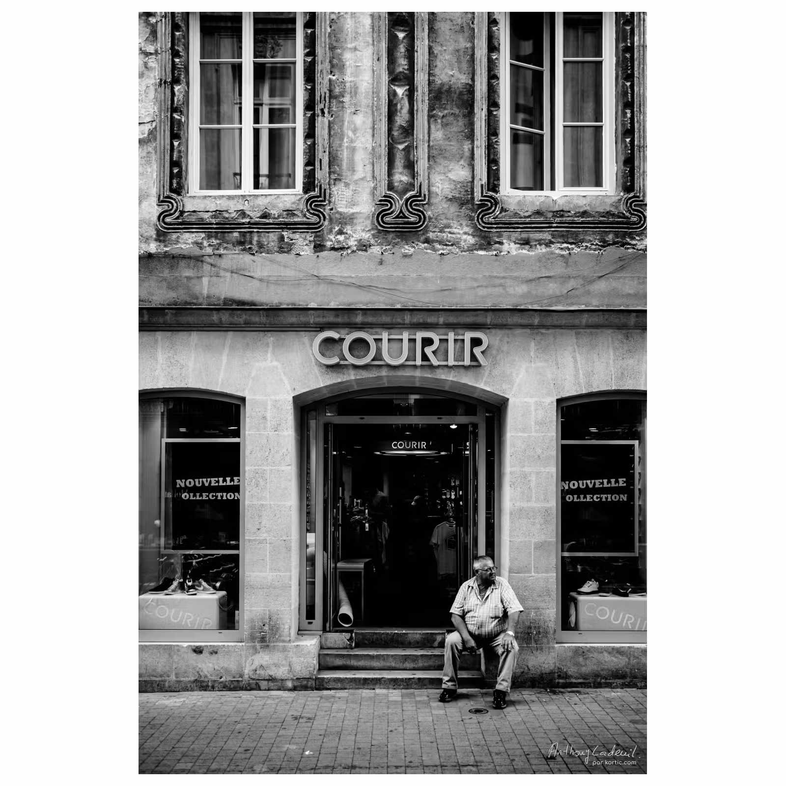 un homme corpulent est assis devant un magasin de vente de chaussures de sport