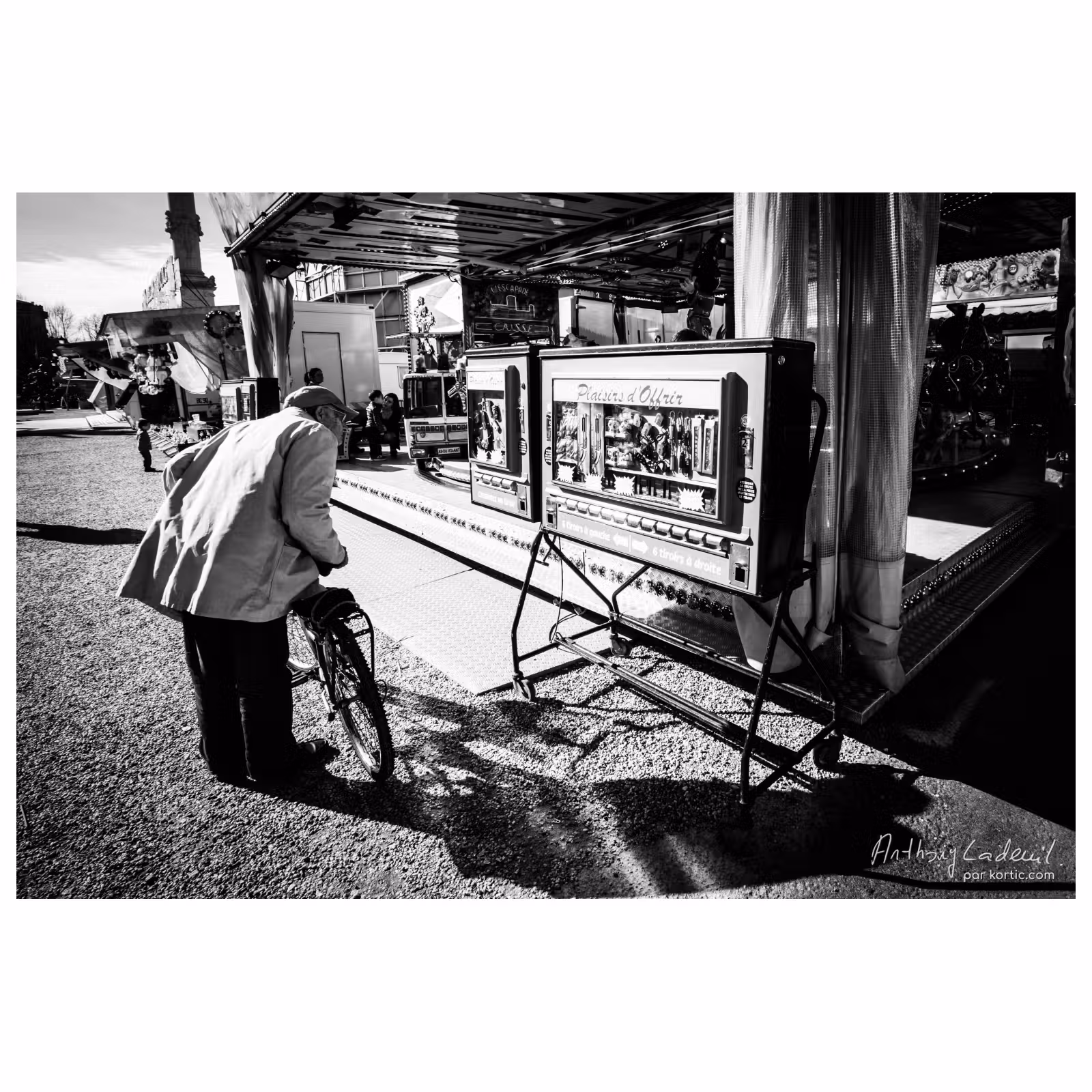 vieil homme et son vélo qui regarde une machine ancienne à tirettes dans une fête foraine