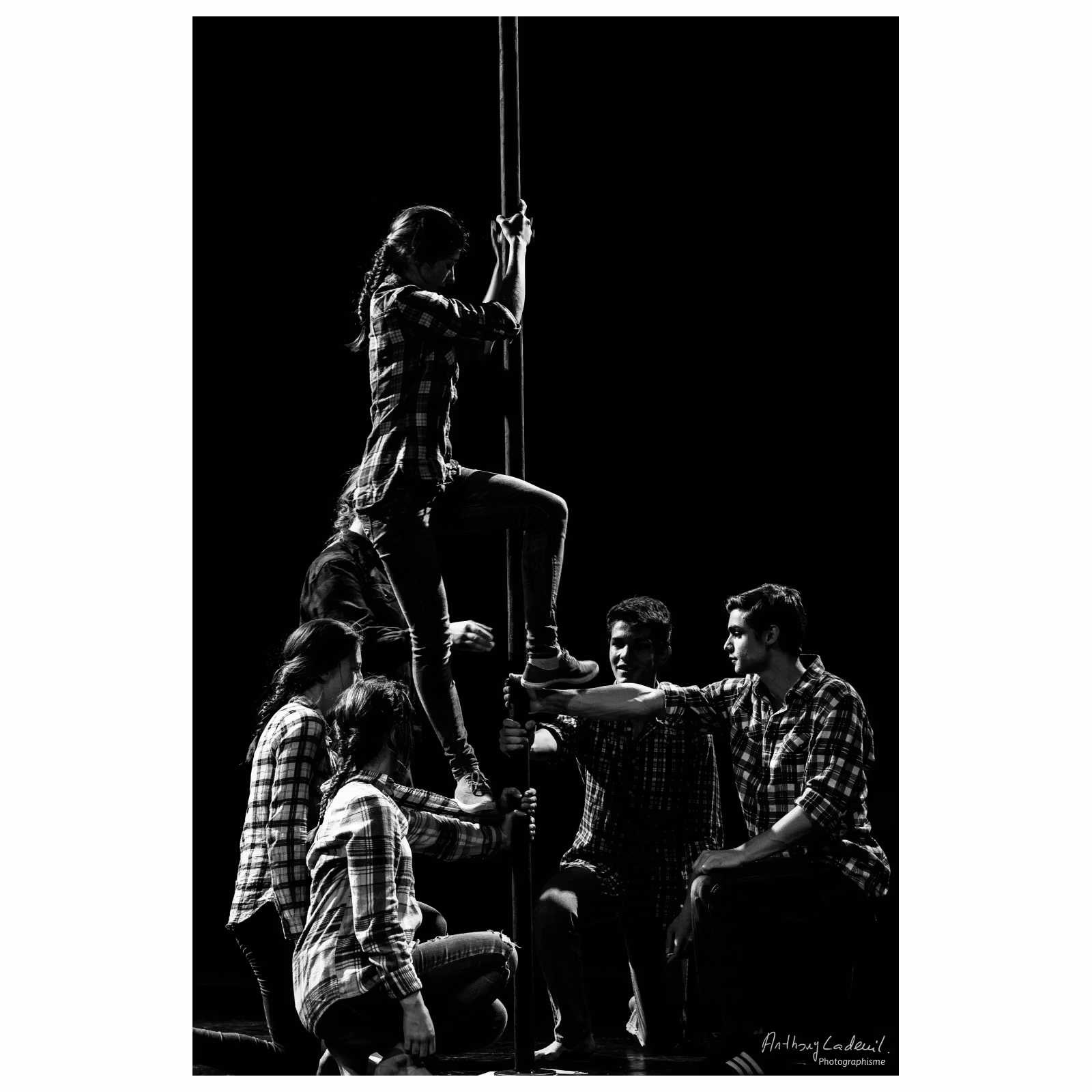 jeunes artistes de cirque tenant un poteau sur lequel monte une jeune femme