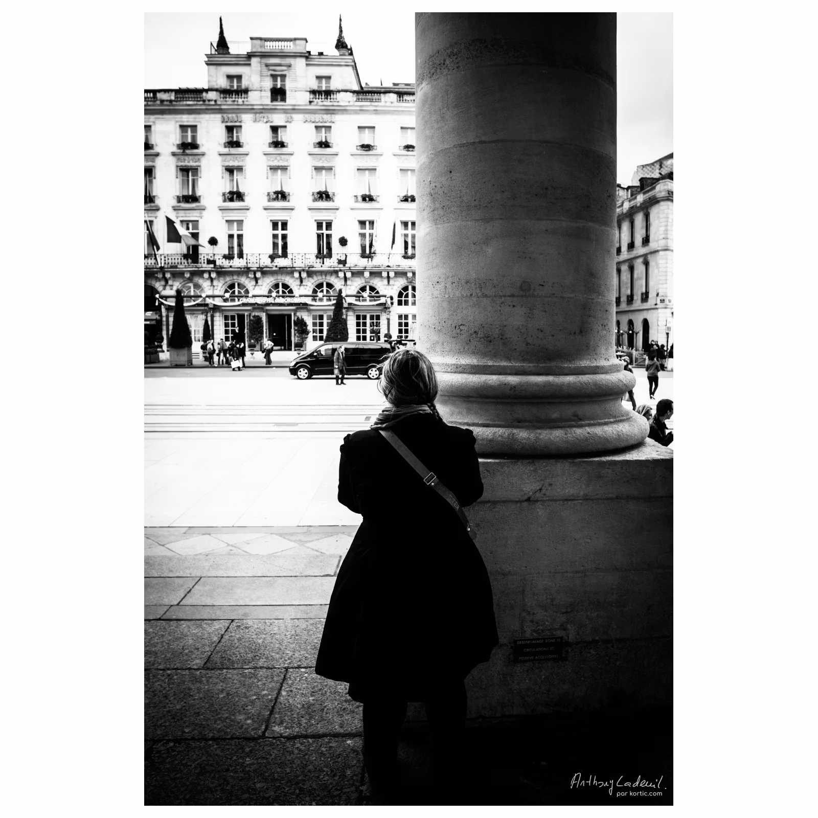 femme de dos cachée derrière une colonne en pierre