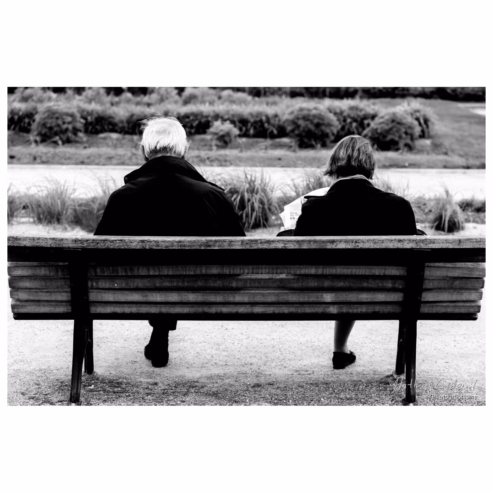 deux personnes de dos assises sur un banc public donnant l'impression de n'avoir qu'une jambe chacun