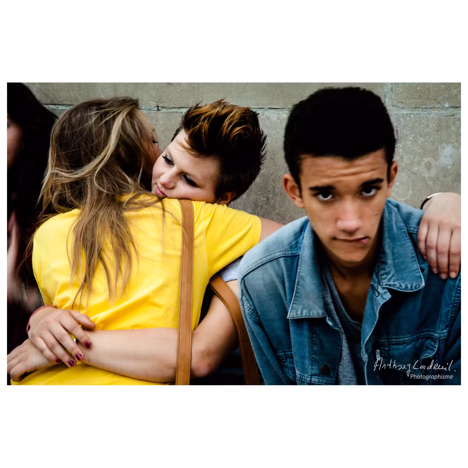 portrait de rue d'un jeune homme assis à côté de deux jeunes femmes s'embrassant