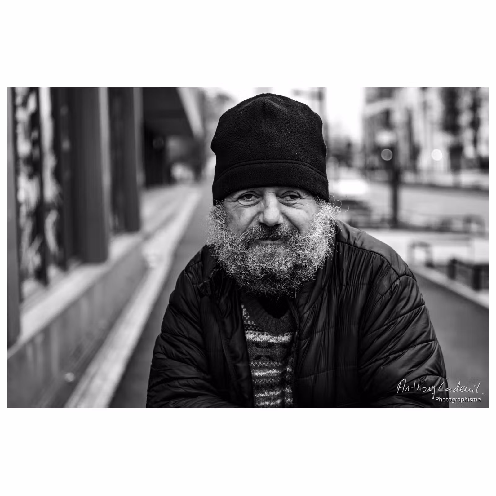 portrait en noir et blanc d'un sans domicile fixe souriant avec un bonnet