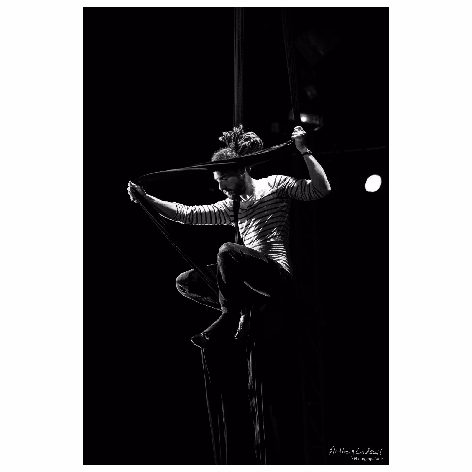 jeune homme artiste de cirque effectuant une figure sur un ruban de tissu