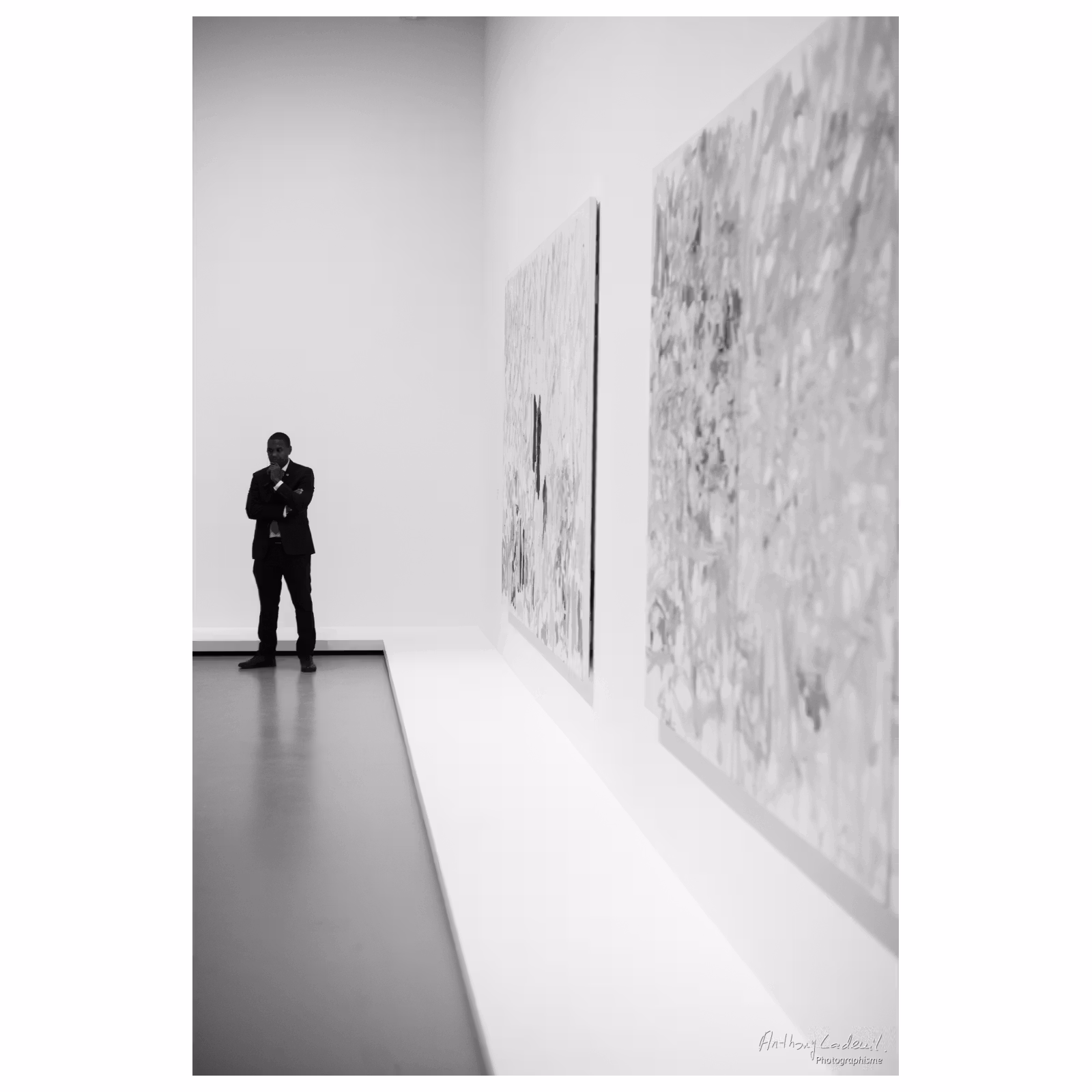 photographie en noir et blanc d'un gardien de musée à proximité de grandes toiles exposées