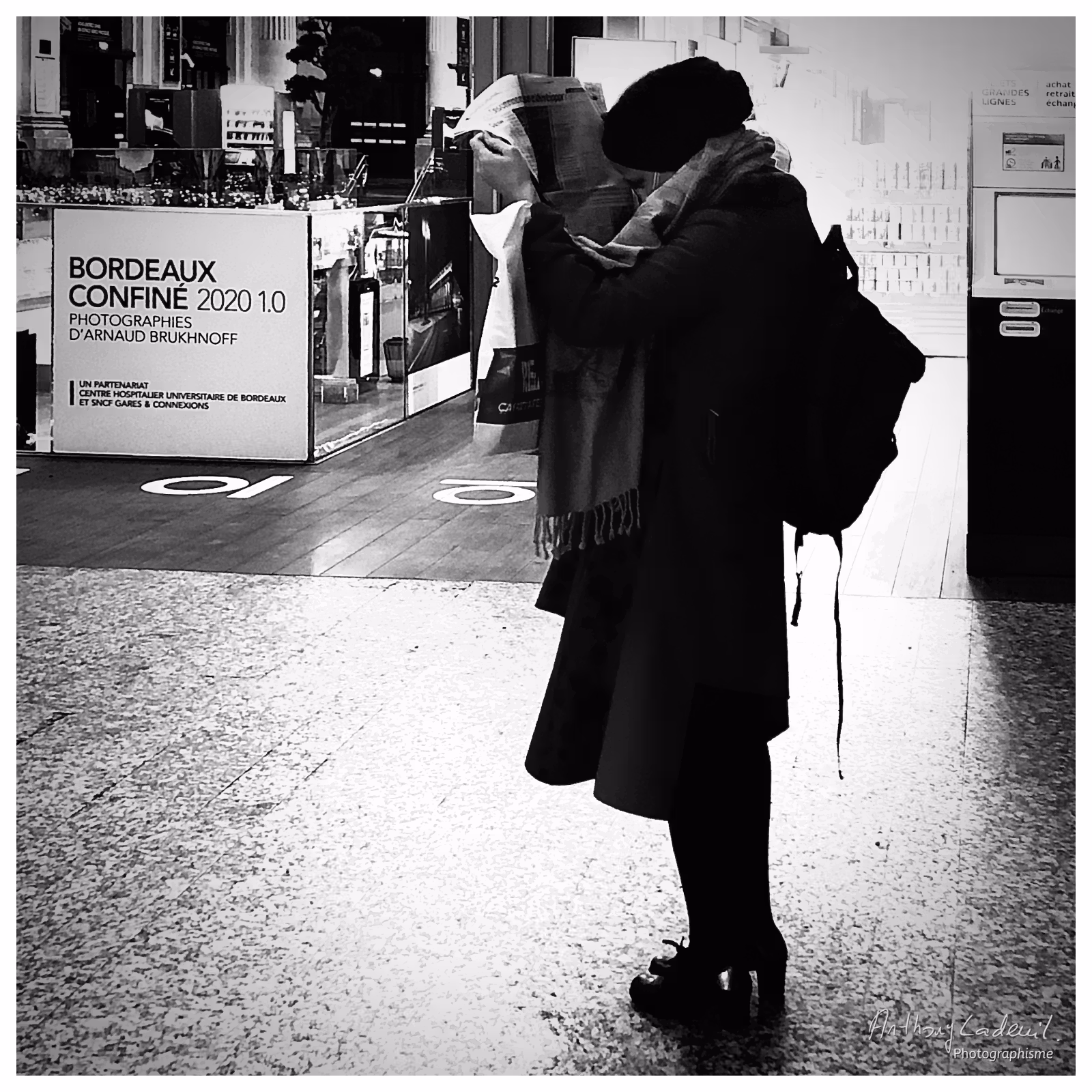 Une femme lit un journal dans le hall de la gare de Bordeaux