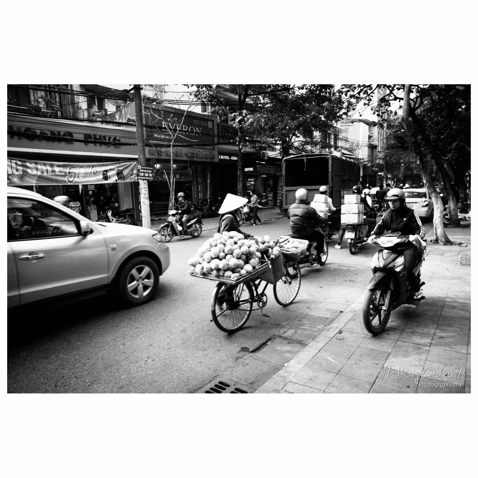 rue de Hanoï où une moto roule sur le trottoir et un piéton marche sur la route