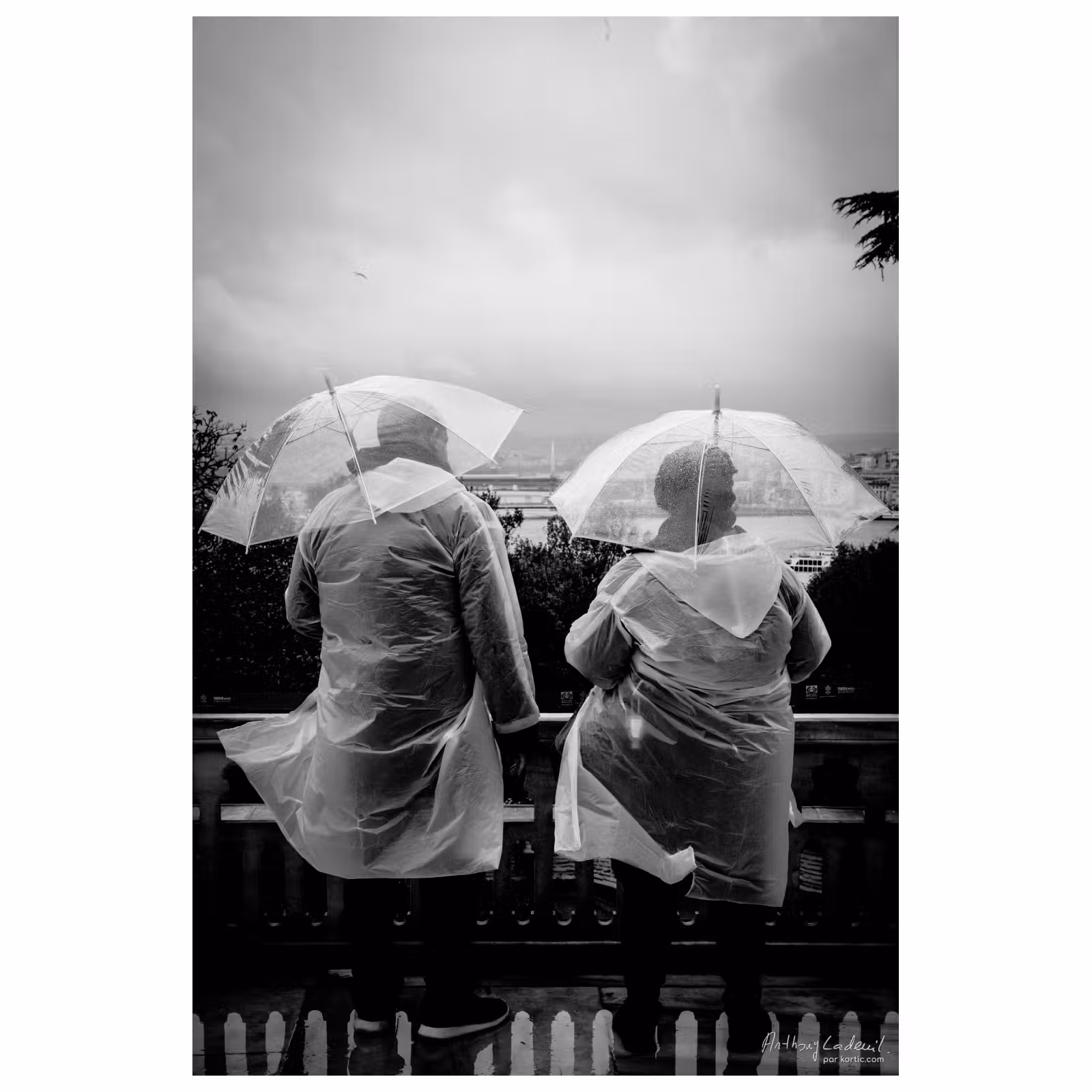 photo de deux touristes vus de dos revêtus chacun de ponchos transparents avec des parapluies