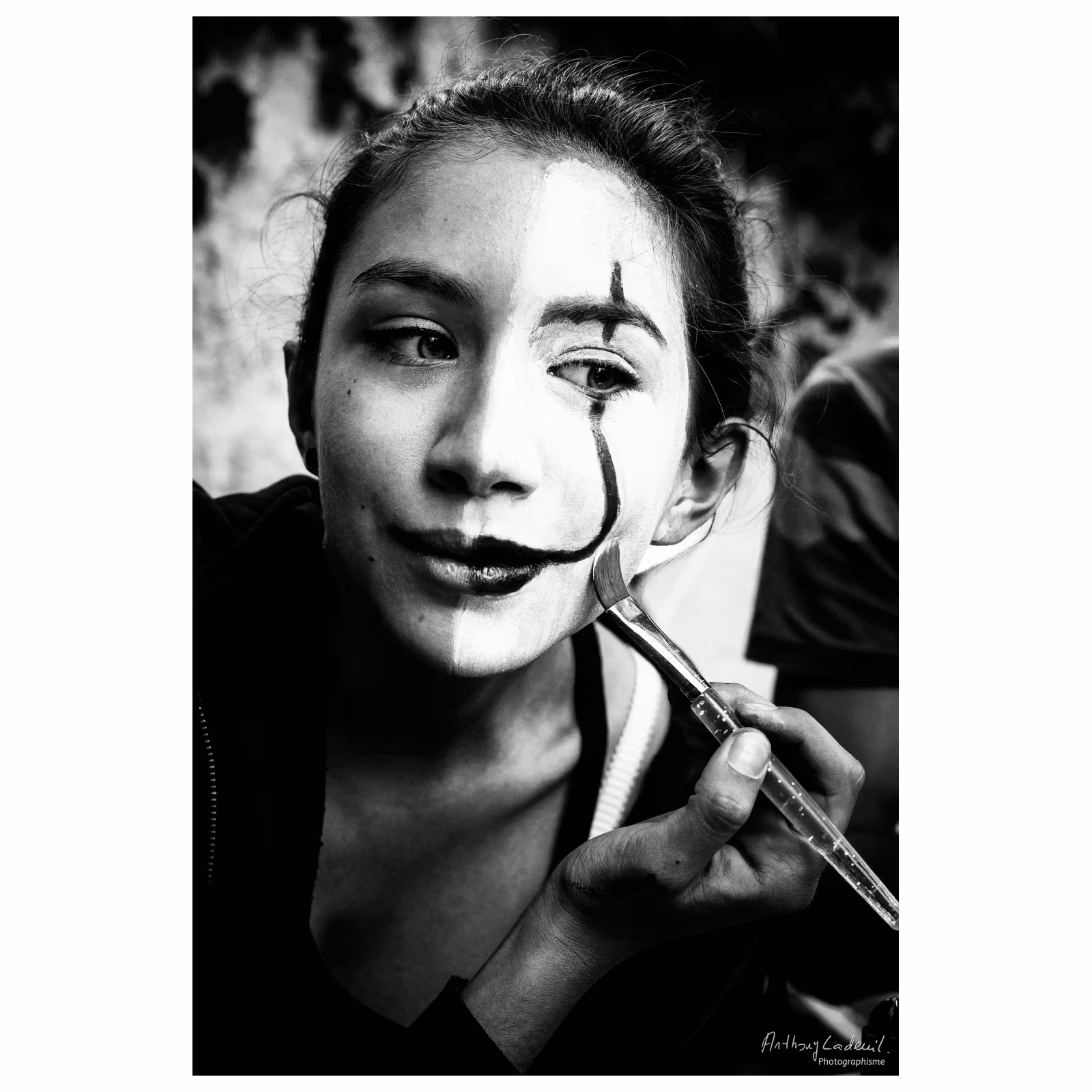 Portrait noir et blanc d'une jeune fille se maquillant la moitié du visage