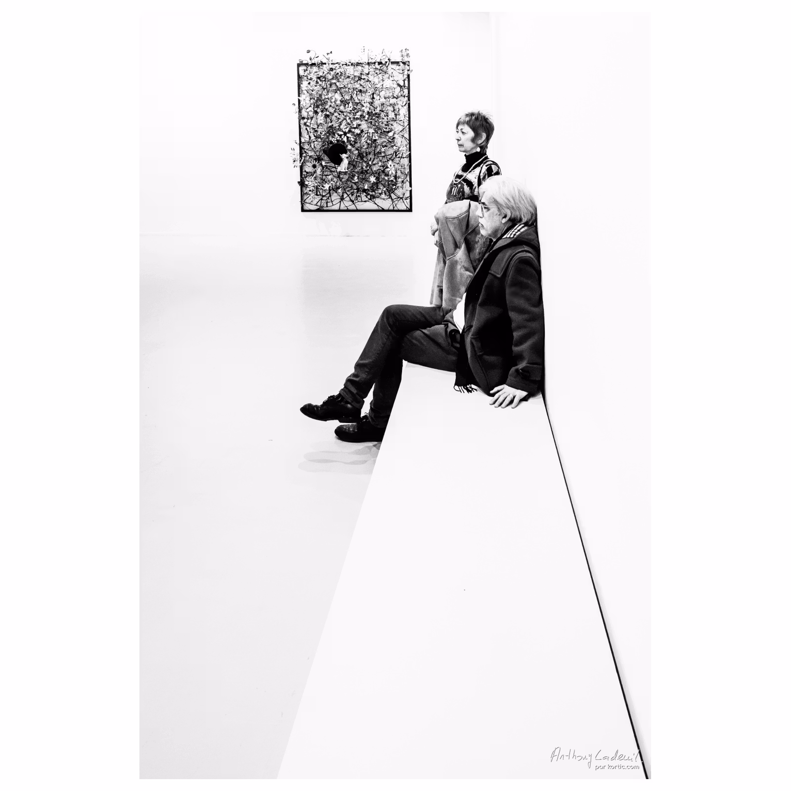 Photo d'une personne assise sur un banc dans une exposition d'art