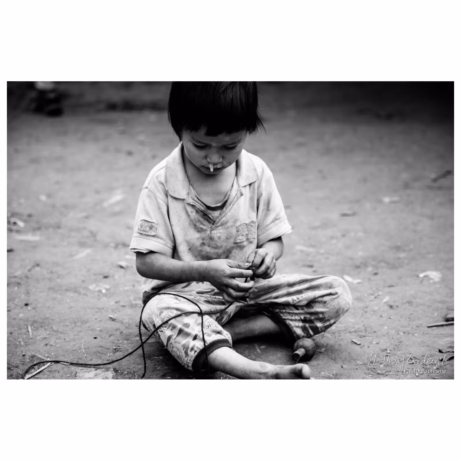 enfant vietnamien jouant à la toupie sur la terre battue