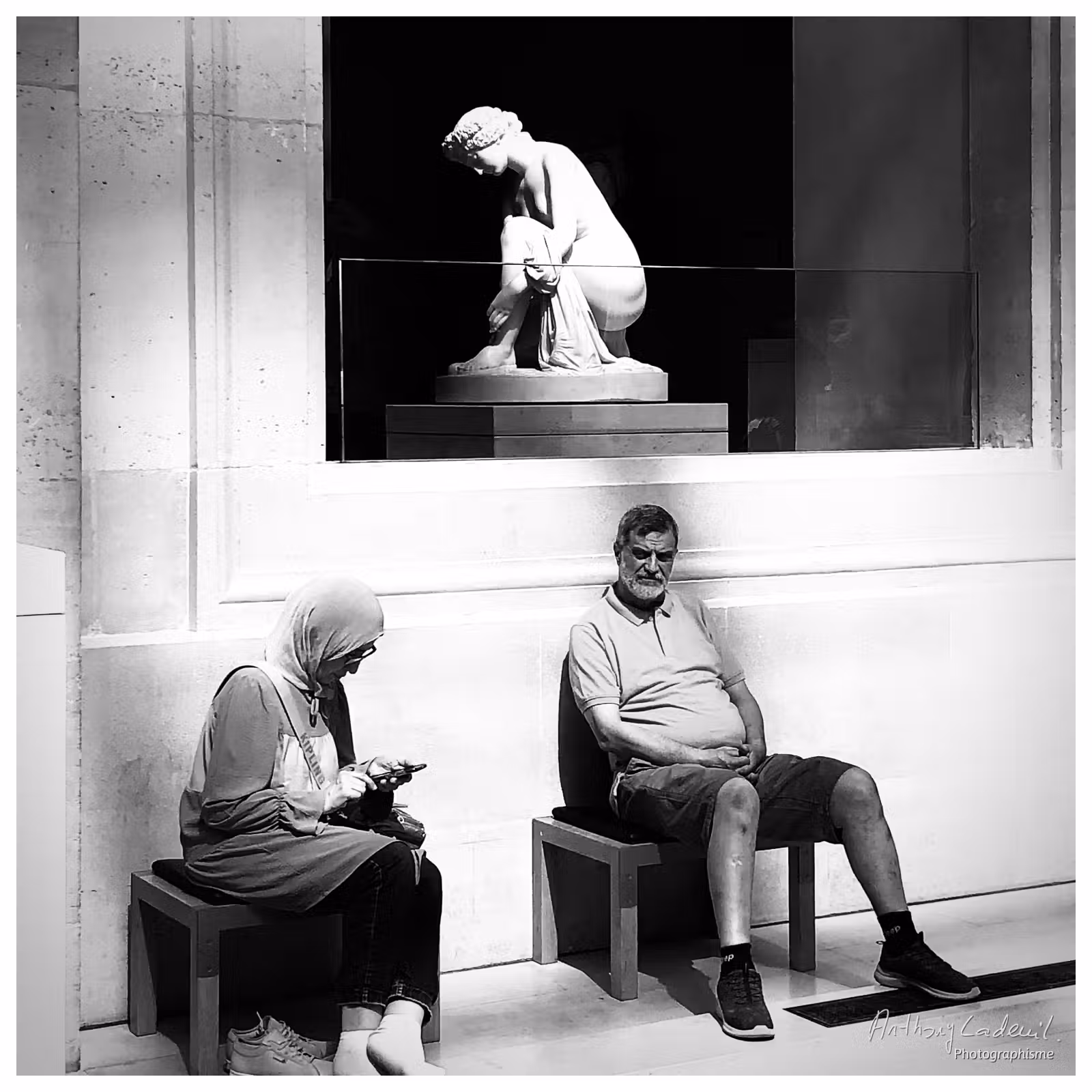 photographie d'un couple assis au pied d'une statue au musée du Louvre