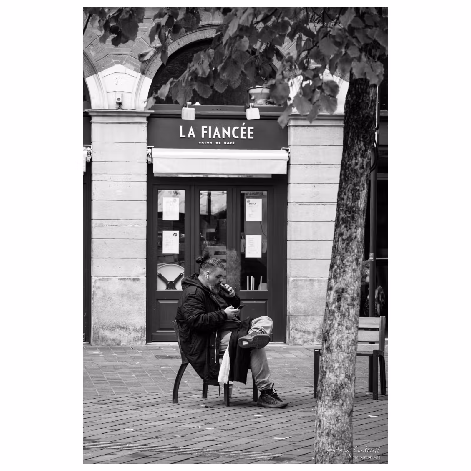 photographie d'un homme assis sur un banc devant un magasin nommé « la fiancée »