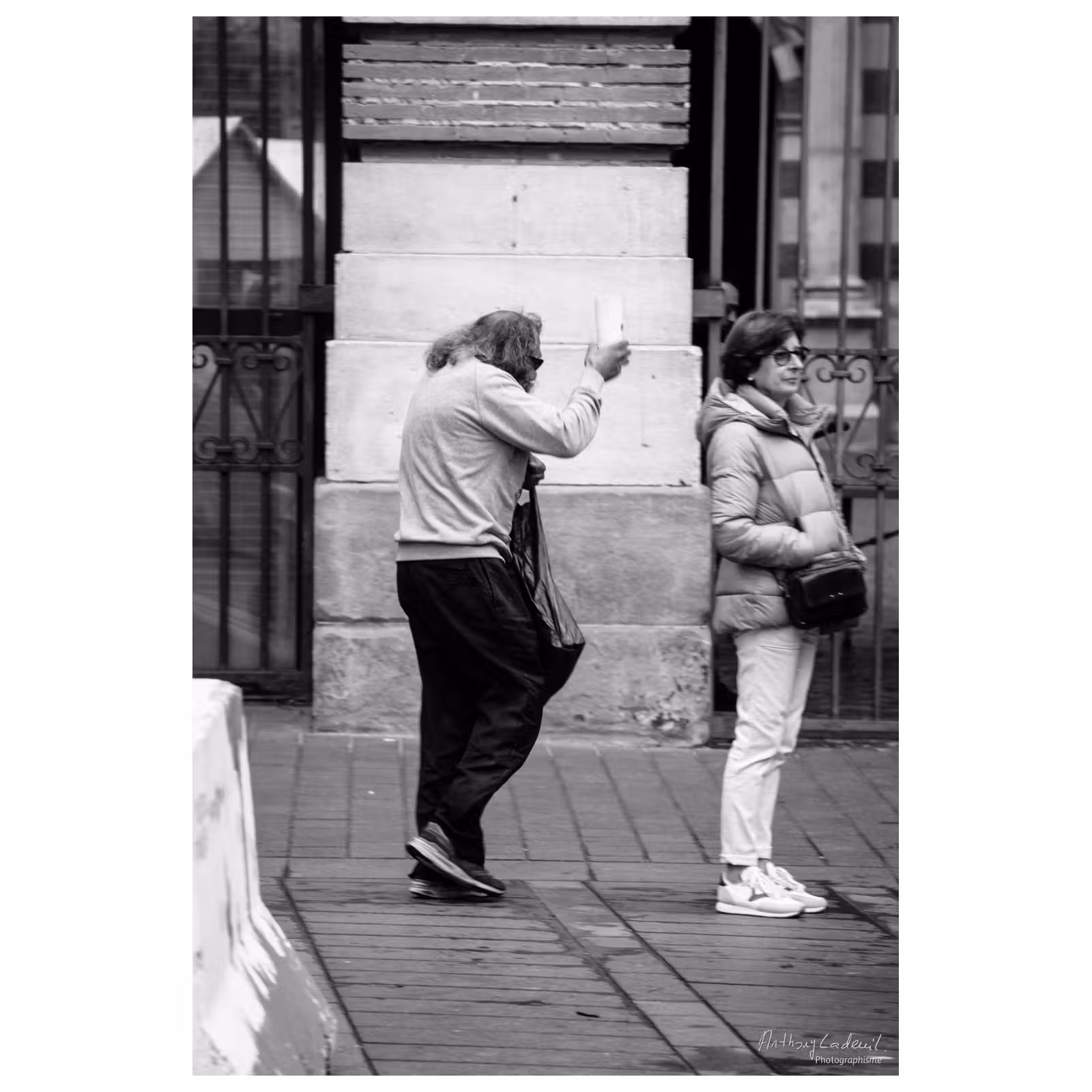 photographie d'un homme tenant un gobelet en carton dans la rue