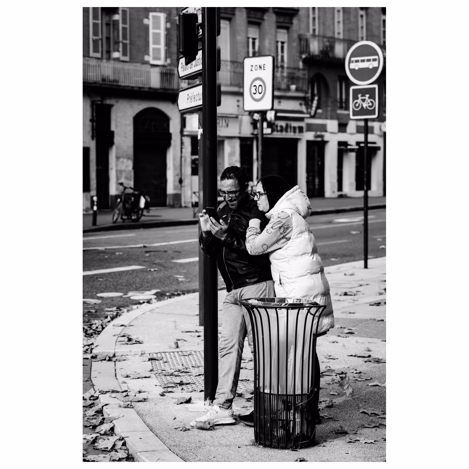 un couple souriant regarde un téléphone à l'angle d'une rue