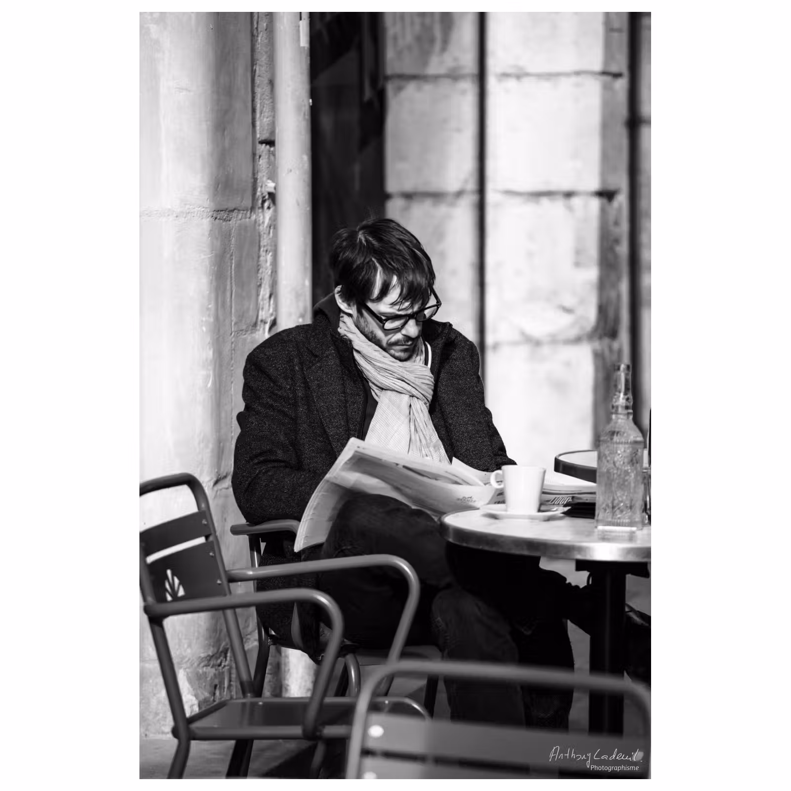 photographie d'un homme lisant le journal sur une terrasse