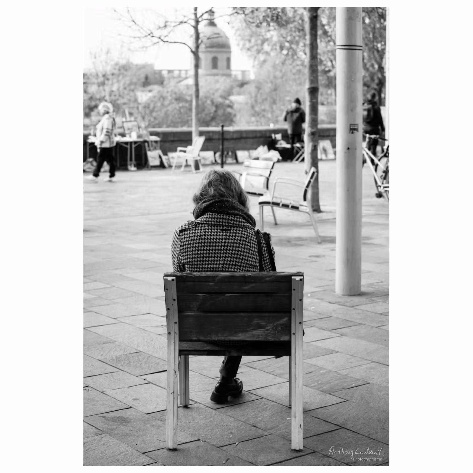 photographie noir et blanc d'une personne de dos sur un banc