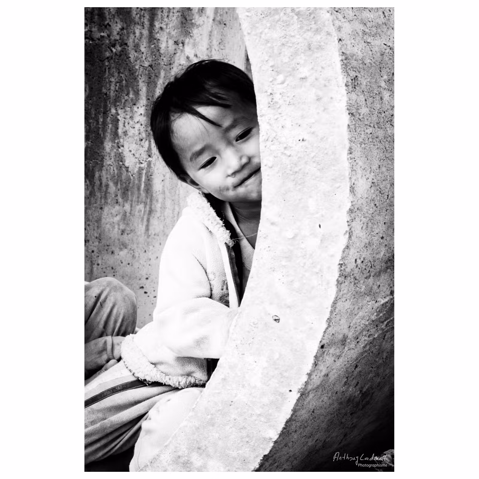 portrait d'un enfant vietnamien jouant dans un tube de béton