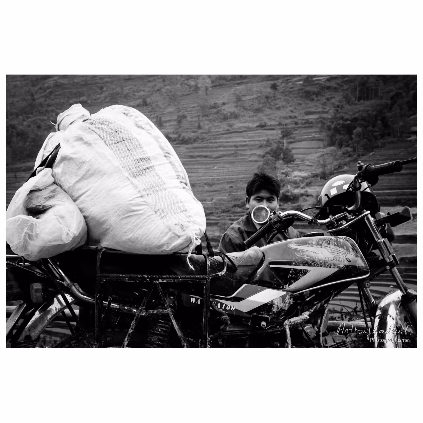 portrait d'un homme vietnamien assis derrière sa moto chargée de colis