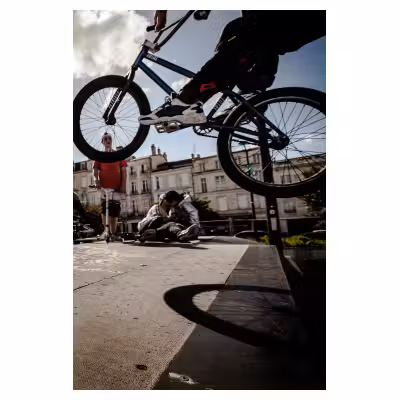 adolescent effectuant un saut à vélo BMX sur un tremplin avec des jeunes en arrière plan