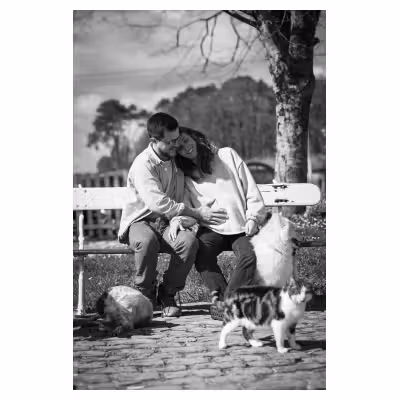 photographie noir et blanc d'un couple de jeunes parents s'enlaçant sur un banc, dont la femme est enceinte. Des animaux domestiques les entourent.