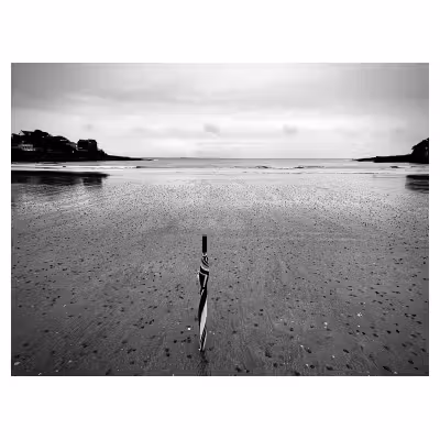Plage de Saint Palais en noir et blanc, à marée basse, avec un parapluie planté dans le sable