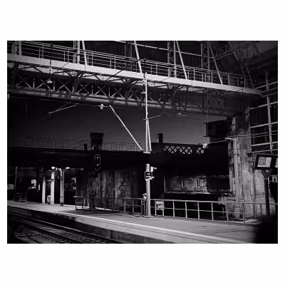 photographie en noir et blanc d'un quai de gare et une verrière métallique