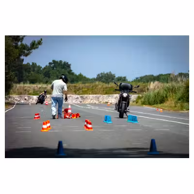 un jeune homme ramasse des plots de slalom sur une piste de formation moto