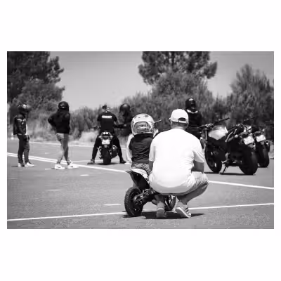 photo noir et blanc d'un jeune enfant sur une mini moto avec son père