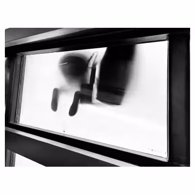 photographie en noir et blanc en contre-plongée sous une passerelle semie transparente où on voit des pieds en contre jour
