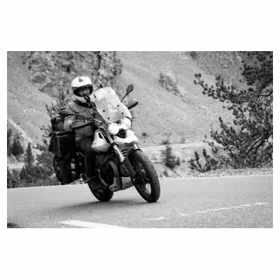 photo noir et blanc d'un motard sur une Moto Guzzi V85 TT chargée de bagages