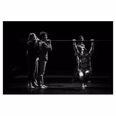 jeunes artistes de cirque tenant une barre sur laquelle est suspendu un garçon