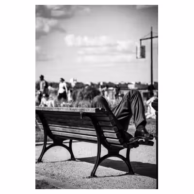 Photographie de rue sur les quais de Bordeaux. Un homme allongé sur un banc.